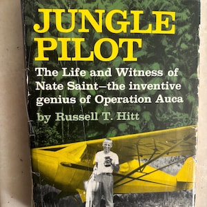 Peut inclure: Un livre vintage intitulé "Jungle Pilot" avec une couverture jaune et verte. La couverture présente le titre en grandes lettres jaunes, le nom de l'auteur et une image d'un avion jaune et d'un homme. Le thème du livre est la vie de Nate Saint.