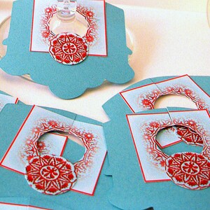 May include: Set of blue and white paper gift tags with red and white snowflake designs. The tags have a hole punched at the top for string or ribbon.