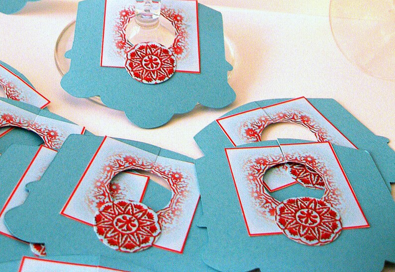 May include: Set of blue and white paper gift tags with red and white snowflake designs. The tags have a hole punched at the top for string or ribbon.