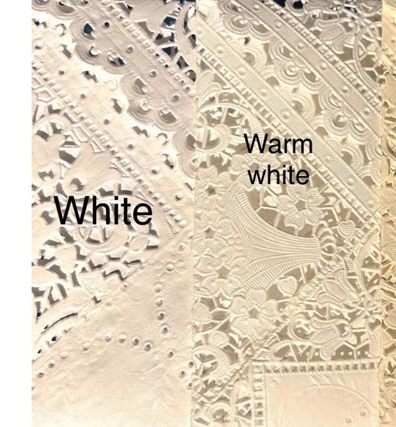 May include: Close-up of white and warm white lace fabric samples. The samples showcase intricate floral and geometric patterns. The text "White" and "Warm white" are visible on the image, highlighting the color variations.