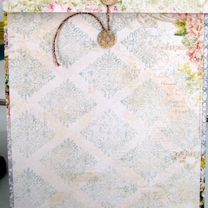 May include: A white envelope with a decorative pattern of blue and white floral designs. The envelope has a brown string tied around it with two small buttons.