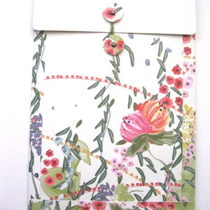 May include: A white envelope with a floral pattern and two fabric buttons. The envelope has a white flap with a floral pattern on the inside.