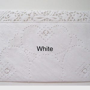 May include: A white, rectangular doily with intricate floral and heart-shaped cutouts. The top edge features a delicate lace design with bows and floral patterns. The word "White" is printed in the center.