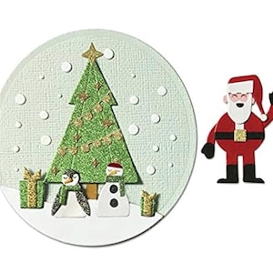 May include: A Christmas-themed paper cutout featuring a green glittery Christmas tree with gold star and garland, a penguin, a snowman, and two wrapped gifts. A separate cutout of Santa Claus in red and black is also present. The background is a light blue circle with white snow.