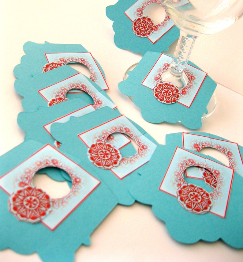 May include: A set of teal blue paper gift tags with red and white snowflake designs. The tags have a hole punched in the top for string or ribbon.
