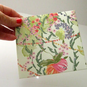 May include: A white envelope with a floral pattern in shades of pink, red, green, and yellow. The flowers are stylized and have a watercolor effect.