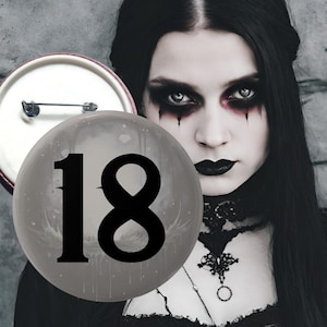 Può includere: Un bottone e un oggetto rotondo trasparente con il numero "18" in nero. Lo sfondo presenta una persona con trucco scuro e rossetto nero. La persona indossa un top e una collana neri.