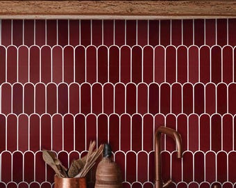 May include: A kitchen backsplash featuring deep red, elongated, rounded-top tiles arranged in a repeating pattern with white grout lines. The wall is positioned behind a wooden countertop, a copper-colored faucet, and a copper-colored utensil holder.