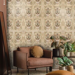 Peut inclure: Un fauteuil marron avec un coussin beige est placé devant un mur recouvert d'un papier peint beige à motif floral répétitif. Le papier peint a un aspect vieilli, avec des zones délavées et une surface légèrement texturée. Il y a des plantes en pot dans la pièce, dont une grande fougère et une plante plus petite aux feuilles vertes.