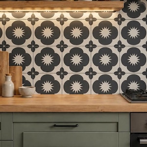 Peut inclure: Intérieur de cuisine avec un plan de travail en bois, des placards verts et une crédence à motifs. La crédence présente un motif floral en noir et blanc. Il y a des planches à découper en bois, des bocaux et des plantes sur le plan de travail et l'étagère.