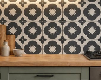 Può includere: Interno cucina con piano di lavoro in legno, armadietti verdi e paraschizzi a motivi. Il paraschizzi ha un motivo floreale in bianco e nero. Ci sono taglieri in legno, barattoli e piante sul piano di lavoro e sulla mensola.