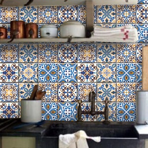 Puede incluir: Un salpicadero de cocina con azulejos de patrones azules y amarillos. Los azulejos tienen un diseño marroquí con detalles intrincados. El salpicadero está detrás de un estante de madera con ollas de cobre y una toalla blanca.