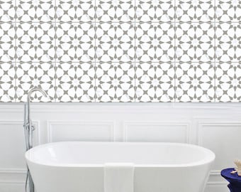 May include: A white freestanding bathtub with a white towel draped over the side, positioned in front of a wall covered in square tiles featuring a repeating geometric star pattern in gray and white. The text BleUcoin is visible in the corner.