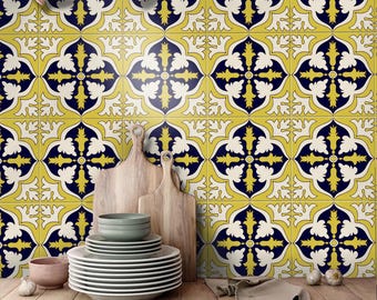 May include: A kitchen backsplash featuring square tiles with a repeating pattern of dark blue, yellow, and white floral motifs. A stack of white plates, a small bowl, two wooden cutting boards, and a beige cloth are arranged on a dark counter.