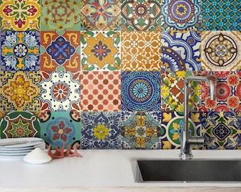 May include: A kitchen backsplash featuring a grid of square tiles with diverse, colorful geometric and floral patterns in shades of blue, yellow, red, and green. A stainless steel faucet and a stack of white plates sit on the white counter.