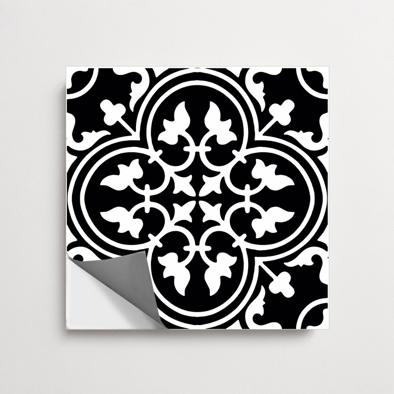 May include: A square tile sticker featuring a high-contrast black and white pattern. The design consists of a central quatrefoil shape surrounded by symmetrical, stylized floral and leaf motifs. One corner of the sticker is peeled back to reveal a gray backing.