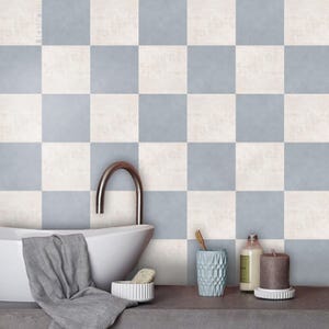Könnte beinhalten: Ein Badezimmer mit einer weißen Badewanne, einem silbernen Wasserhahn und einem grauen Handtuch. Der Hintergrund ist ein Schachbrettmuster aus hellblauen und cremefarbenen Quadraten. Auf einer grauen Arbeitsplatte stehen eine Zahnbürste, ein blauer Becher und Flaschen.