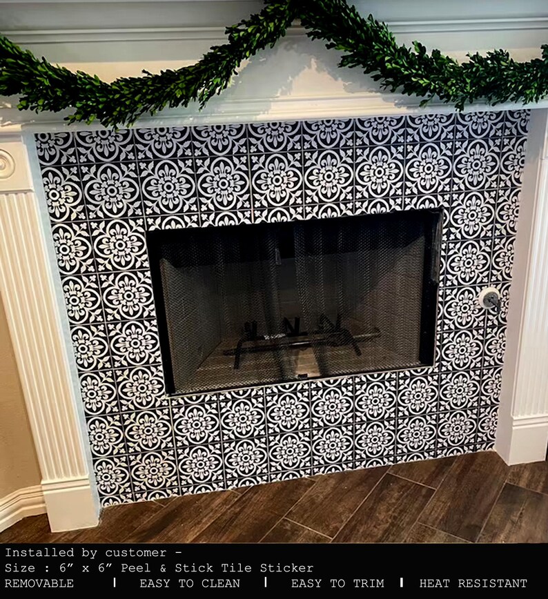 A fireplace with a black screen and white mantel, with the area around the firebox covered in black and white patterned tile stickers.