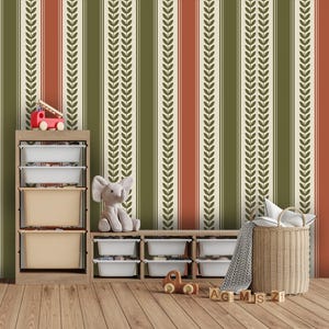 Op de afbeelding: Een kamer met een gestreept behang in groen, crème en rood. Een houten opbergmeubel met witte bakken en een speelgoedbrandweerwagen staat voor de muur. Een knuffelolifant en een rieten mand staan ook in de kamer.