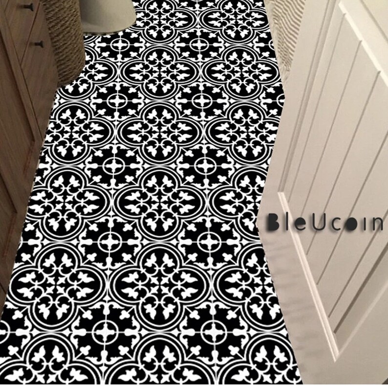 May include: A floor covering featuring a repeating black and white geometric pattern with circular and floral motifs. The design includes a series of interconnected shapes across the surface. The text BleUcoin is visible on the right side.