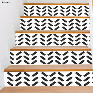 May include: Black and white chevron patterned stair treads. The treads are made of a white material with black chevron patterns. The treads are on a wooden staircase.