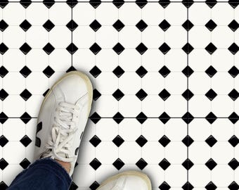 May include: A pair of white sneakers with black accents are standing on a black and white diamond patterned tile floor.