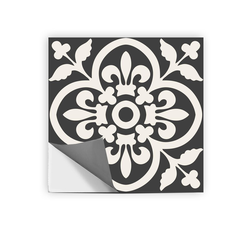 A single black and white patterned tile sticker with one corner peeled back to reveal a gray adhesive backing.