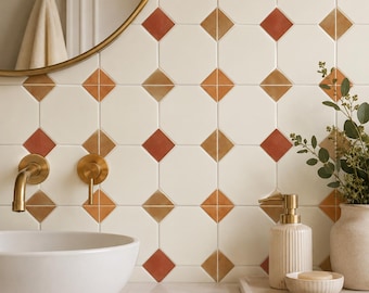 May include: A bathroom vanity area featuring a white vessel sink, a brass wall-mounted faucet, and a soap dispenser on a tray. The wall is covered in white square tiles with small orange and brown diamond-shaped accents between the corners.