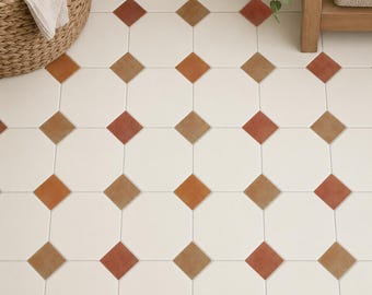 May include: A floor surface covered in white octagonal tiles arranged in a repeating pattern with small, square-shaped accent tiles in shades of terracotta and brown placed at the intersections between the larger white tiles.