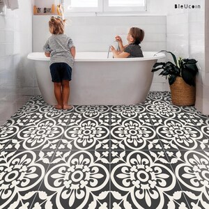 Two children in a bathroom with a white freestanding tub, with the floor covered in black and white patterned tile stickers.