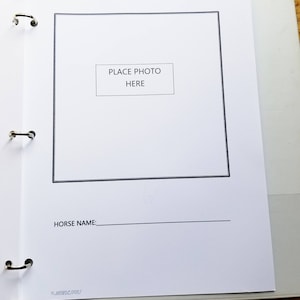May include: A white page with a black border around a blank space for a photo. The text "PLACE PHOTO HERE" is in the centre of the blank space. Below the photo space is the text "HORSE NAME:" followed by a blank line.