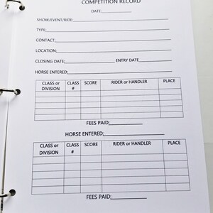 May include: A white competition record log book with black text. The book has sections for show/event/ride, type, contact, location, closing date, entry date, horse entered, class or division, class number, score, rider or handler, place, and fees paid.