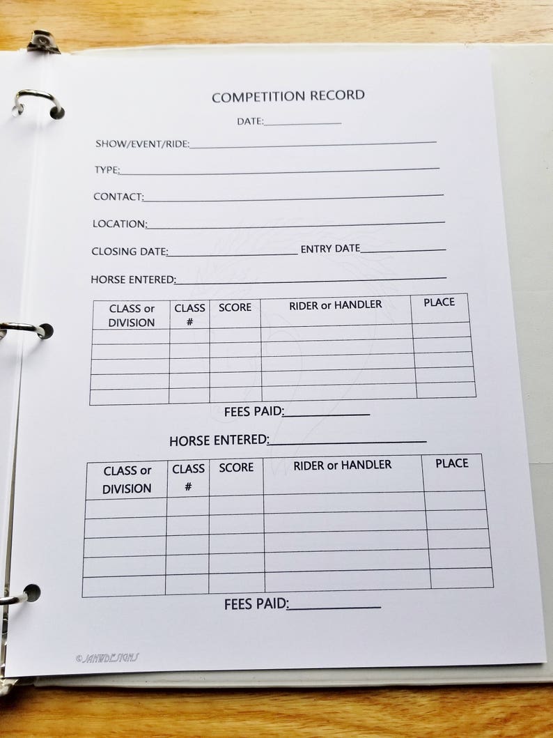 May include: A white competition record log book with black text. The book has sections for show/event/ride, type, contact, location, closing date, entry date, horse entered, class or division, class number, score, rider or handler, place, and fees paid.