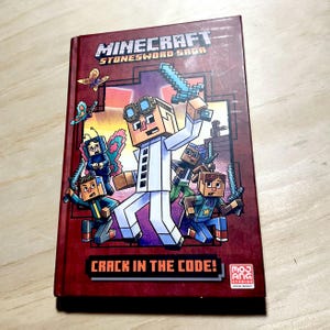 May include: A hardcover book titled "Minecraft Stonesword Saga" with a red cover. The cover features pixelated characters with swords and the text "Crack in the Code!". A butterfly graphic is also visible.