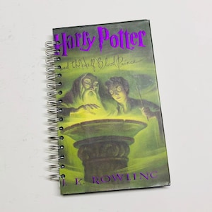 May include: A spiral bound notebook with a Harry Potter and the Half-Blood Prince book cover. The cover features a green and black illustration of Harry Potter and Professor Dumbledore.