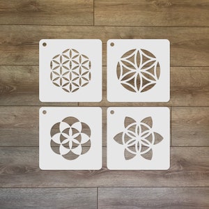 May include: Four white square stencils featuring different geometric designs. The designs are all variations of the flower of life pattern.