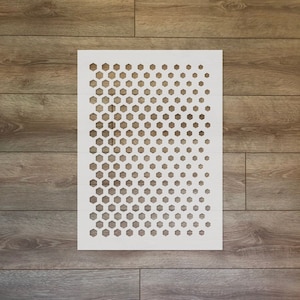 May include: White stencil with a repeating pattern of hexagonal shapes. The stencil is on a wood background.