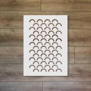May include: White stencil with a repeating pattern of semi-circles. The stencil is designed for crafting and decorating projects.
