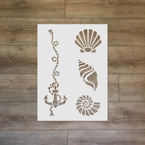 Op de afbeelding: Een witte stencil met een nautisch thema. De stencil bevat een schelp, een touw met knopen, een anker en een spiraalvormige schelp.