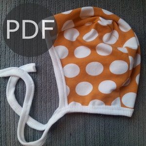 May include: A baby bonnet with an orange background and large white polka dots. The bonnet has a white ribbed trim and white ties. The word "PDF" is in a gray circle in the upper left corner.