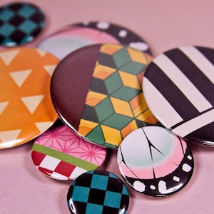 May include: A collection of eight round button pins with various colorful patterns, including checkered, striped, and geometric designs.