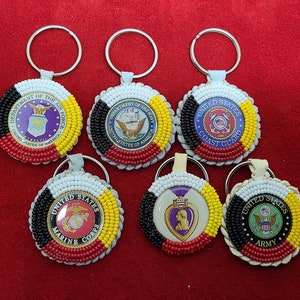 May include: Set of seven beaded keychains featuring the logos of the United States military branches: Air Force, Navy, Coast Guard, Marine Corps, Purple Heart, and Army. Each keychain is made with white, black, red, and yellow beads.