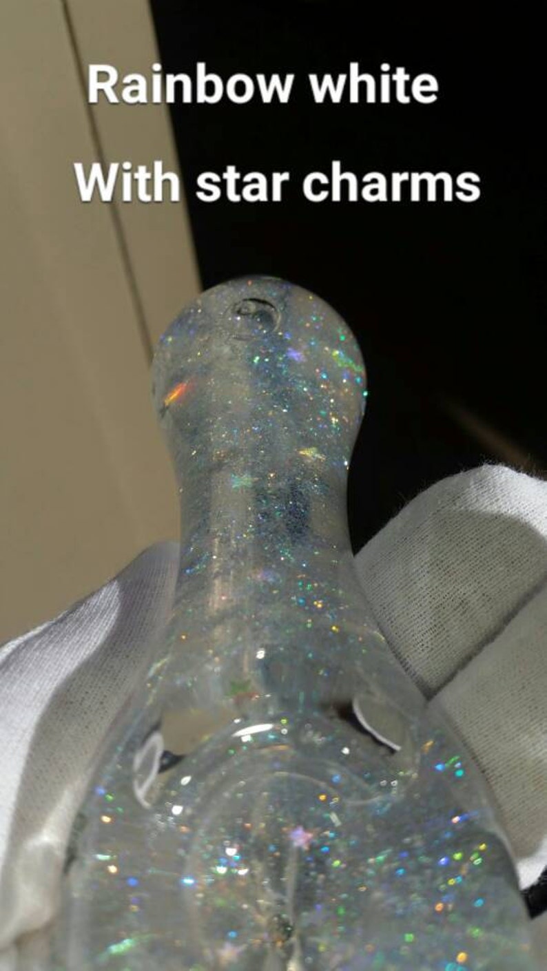 May include: A clear glass pipe with rainbow glitter and star charms. The pipe is white and has a round, bulbous shape.