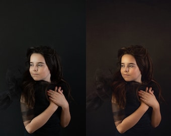 May include: A young person with long brown hair and fair skin, wearing a black top and a sheer black scarf. The person's arms are crossed, and they are looking off to the side against a dark background.