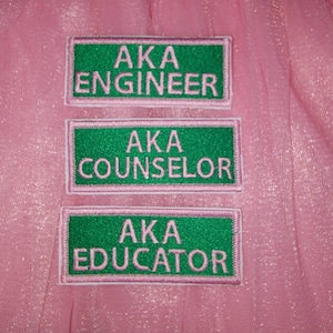 May include: Three pink and green embroidered patches with the text "AKA Engineer", "AKA Counselor", and "AKA Educator".