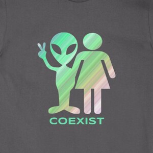 May include: A dark gray t-shirt with a green and blue alien and a human figure with the word "COEXIST" printed below.