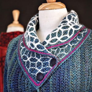 May include: A blue knitted cardigan with a white crocheted collar and a pink trim. The cardigan has a button closure and is displayed on a mannequin.