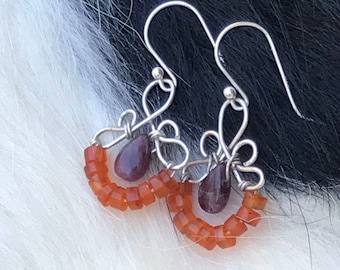 The Emma earring: hand formed sterling silver wire with a purple tourmaline  teardrop bead and a string of orange carnelian stone beads