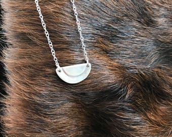 The Adrian necklace made of two small sized half circles layered on the necklace focal point