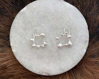 sculpted silver square with solid silver balls adoring the outside of circle